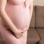 pregnant-woman-in-pink-dress-caressing-her-belly