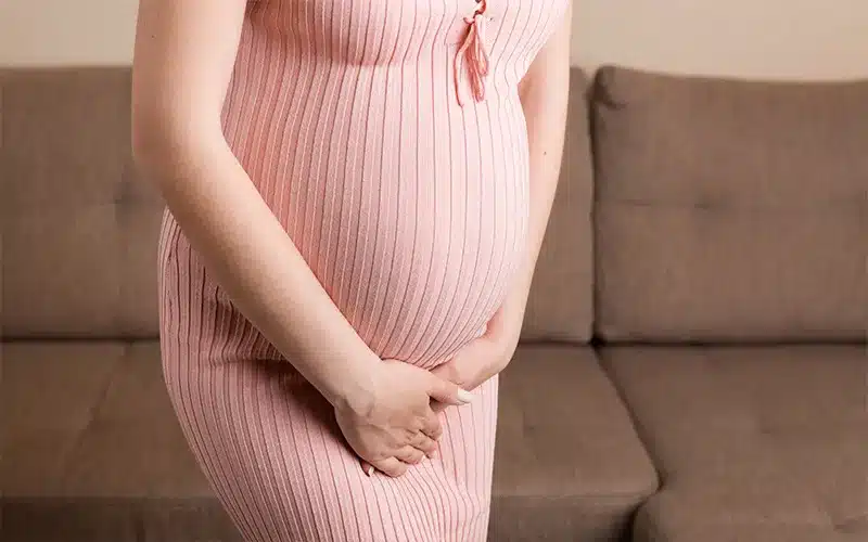 pregnant-woman-in-pink-dress-caressing-her-belly